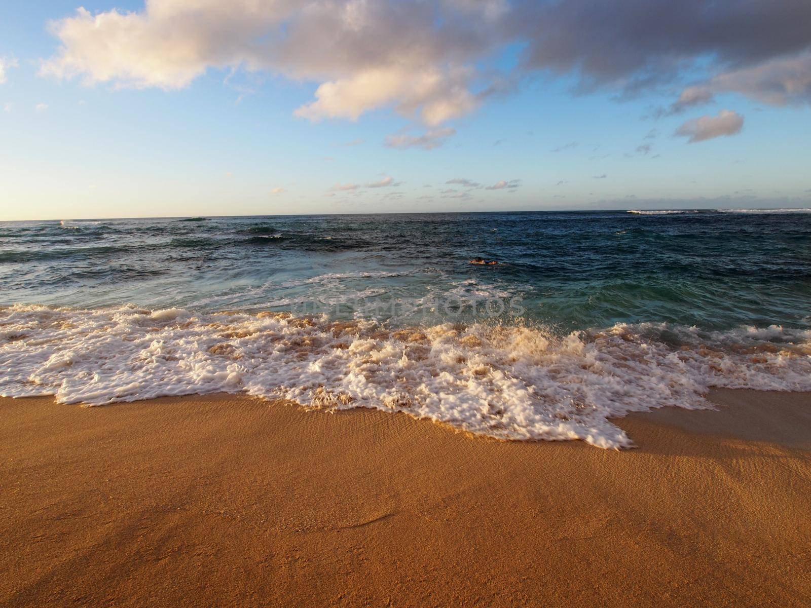 Sea foam forms as Waves move into beach shore looking into the pacific ocean on the north shore of Oahu. 