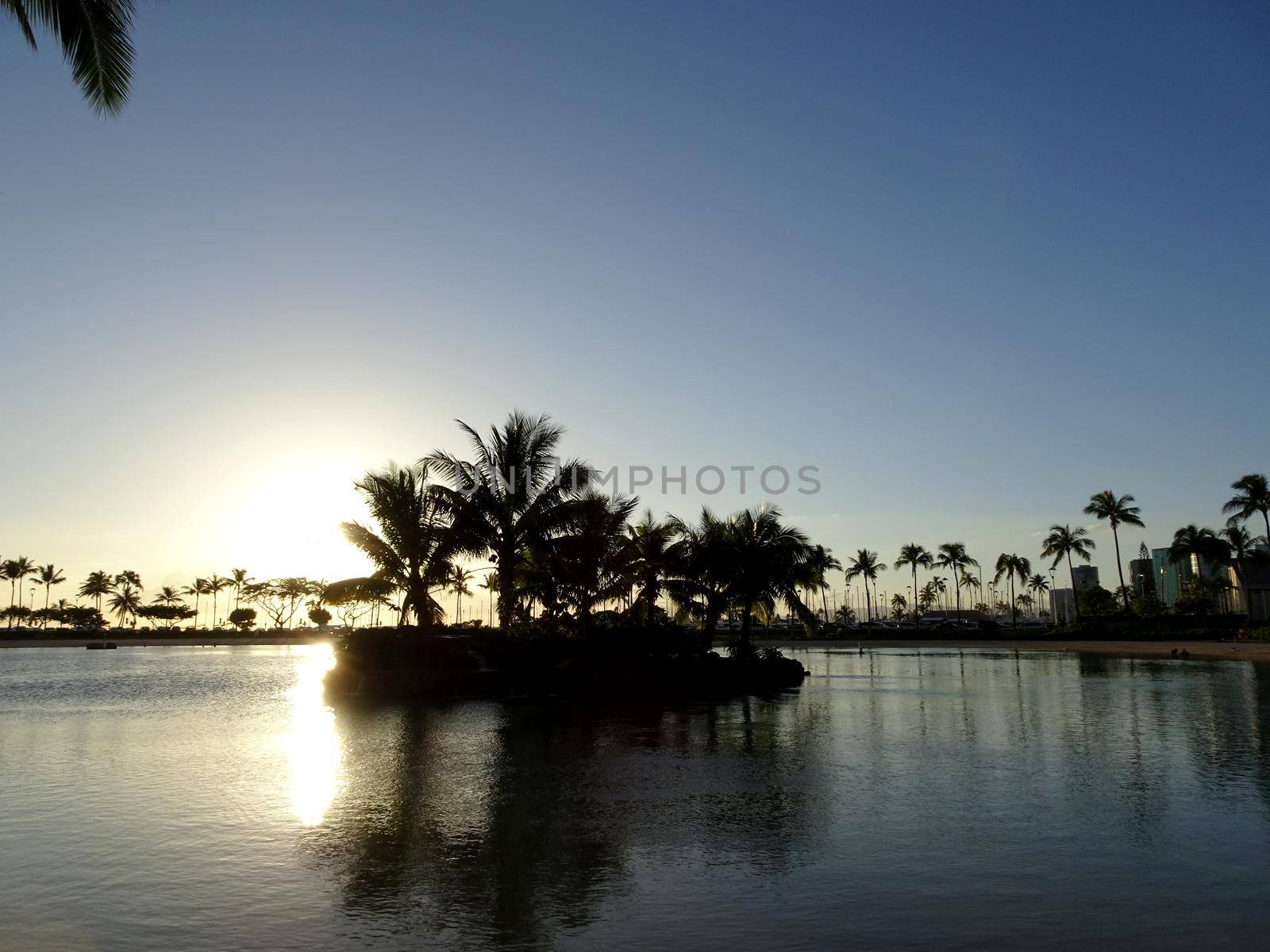 Sunset over Duke Kahanamoku Lagoon reflecting on the water in Waikiki, Hawaii.