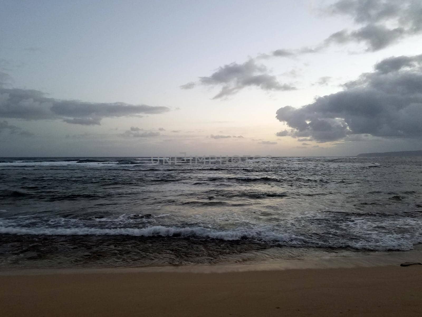 Shallow wavy ocean waters of Camp Mokuleia Beach looking into the pacific ocean with at dusk on Oahu.