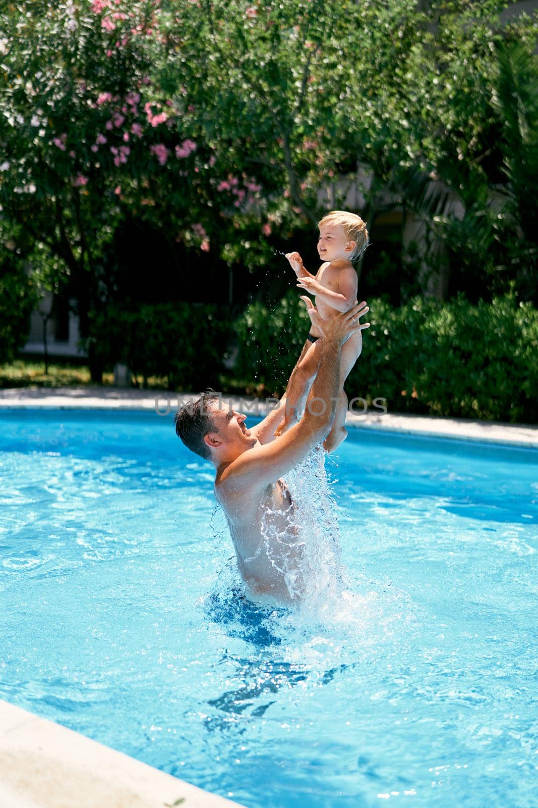 Dad throws a small child in the air over the turquoise water. High quality photo