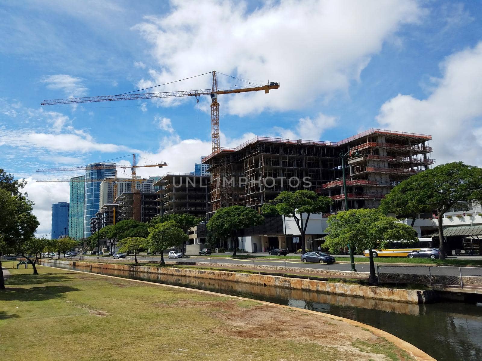 Concrete stream in Ala Moana Beach Park surrounded by trees with Condominiums towers under construction across the street by EricGBVD
