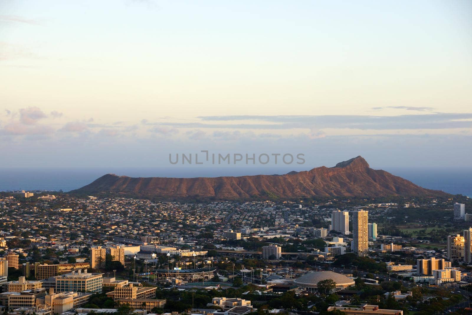 The city of Honolulu from Diamond head to Manoa with Kaimuki, Kahala, and oceanscape visible on Oahu on a nice day at dusk viewed from high in the mountains with tall trees in the foreground.  Seen from Round Top Drive Lookout.  May 17, 2015.