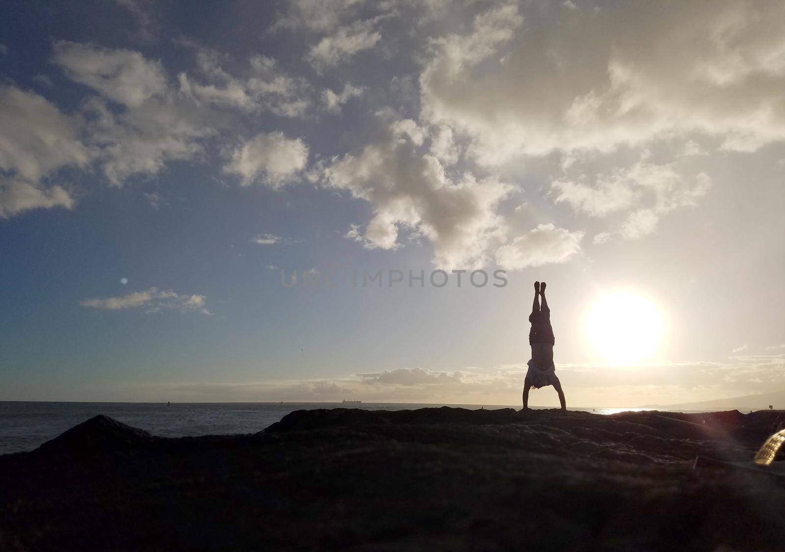 Man Handstanding on coastal rocks at sunset by EricGBVD