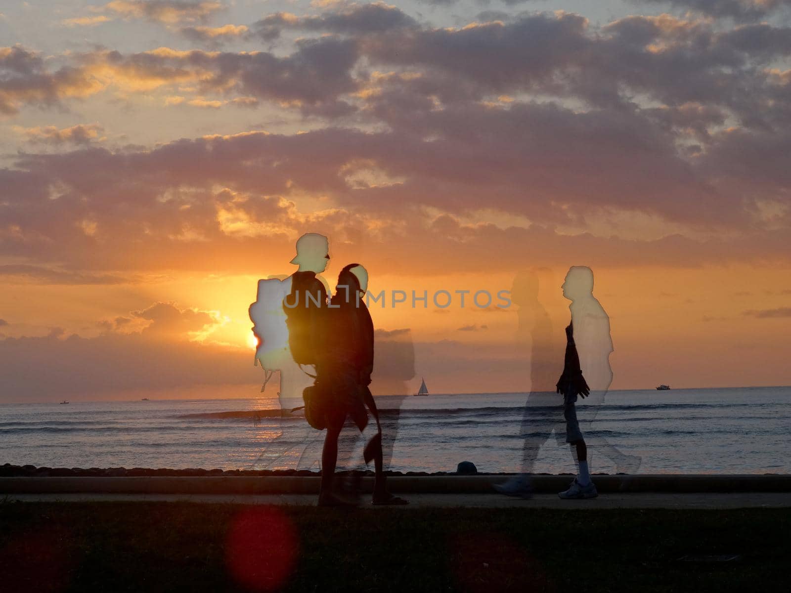 Sunset dropping behind the ocean on Kaimana Beach and images of people walking by with boats on the water by EricGBVD