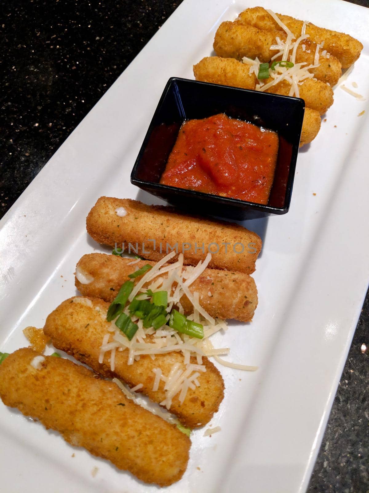 Crispy Mozzarella sticks marinara sauces for dipping on a white plate.