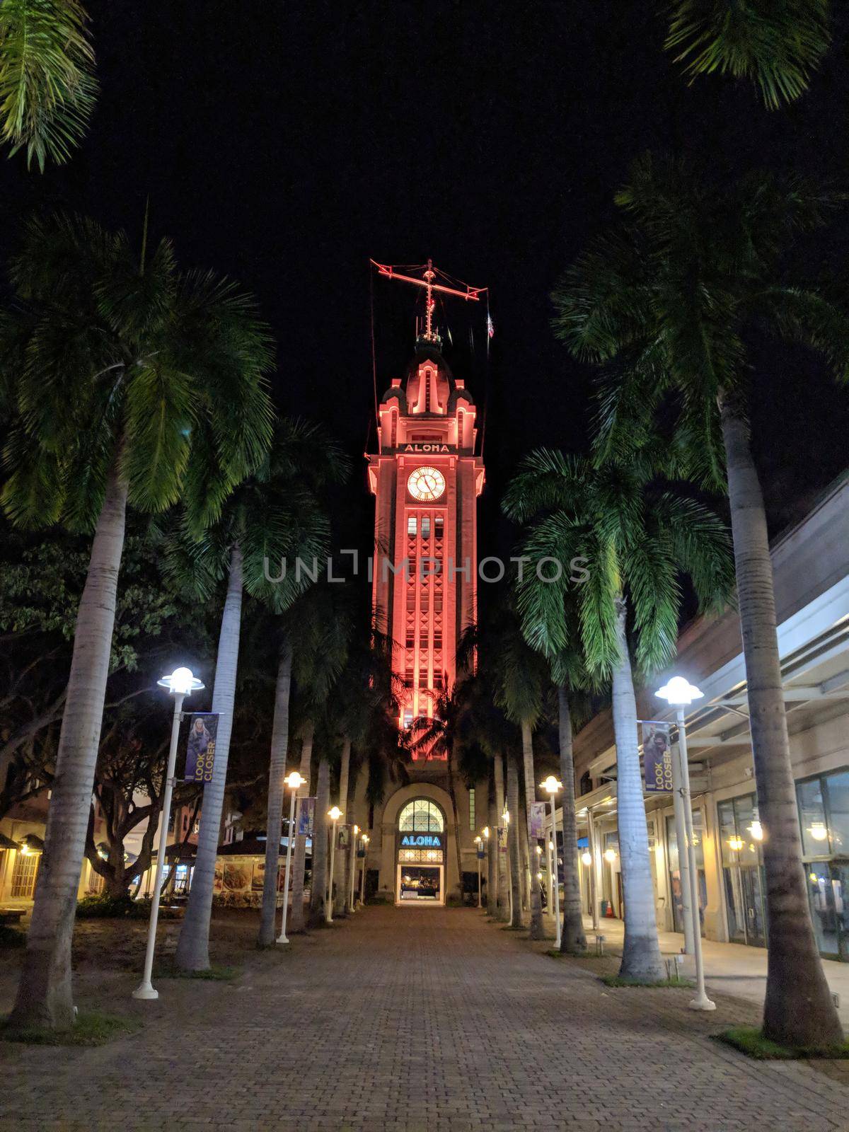 Honolulu - April 18, 2018: Pathway to Aloha Tower at Night which is light up in red and has greeted arriving visitors for a century to Honolulu Harbor on Oahu, Hawaii.  Aloha Tower was the tallest building on the island at the time of its construction.
