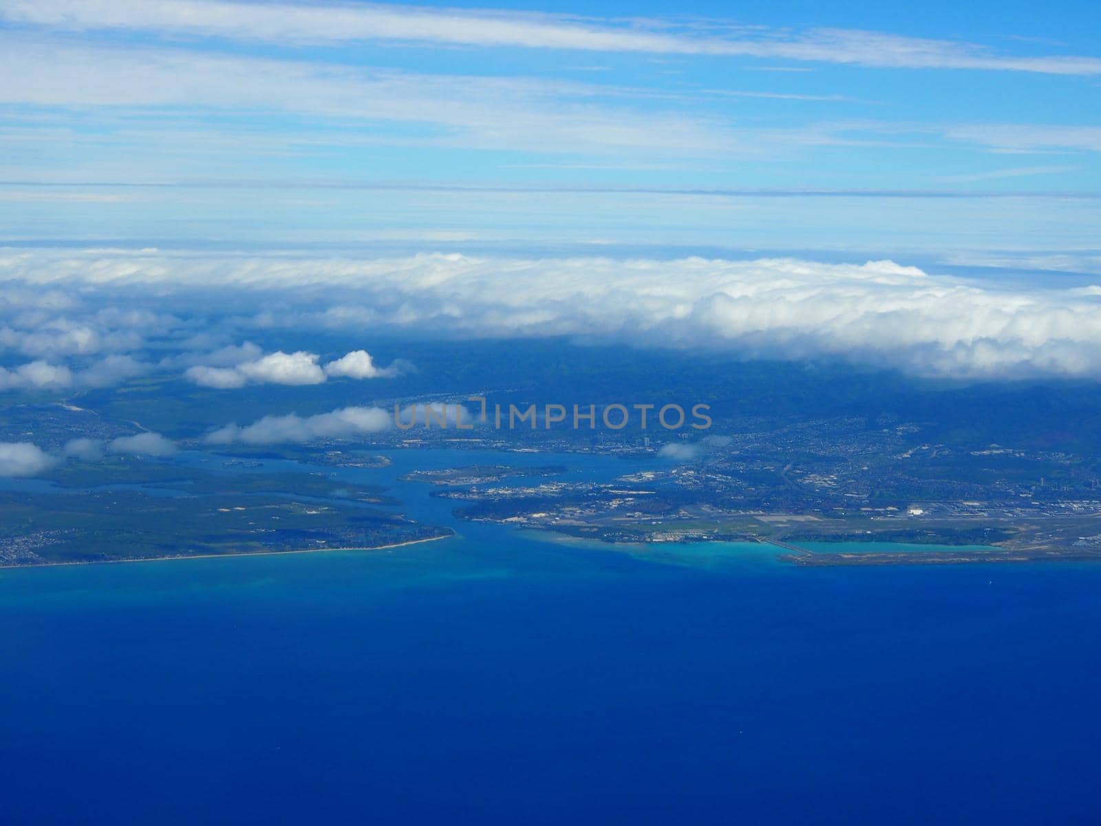 Aerial of Pearl Harbor and Honolulu Airport from the ocean with clouds over the island of Oahu, Hawaii.