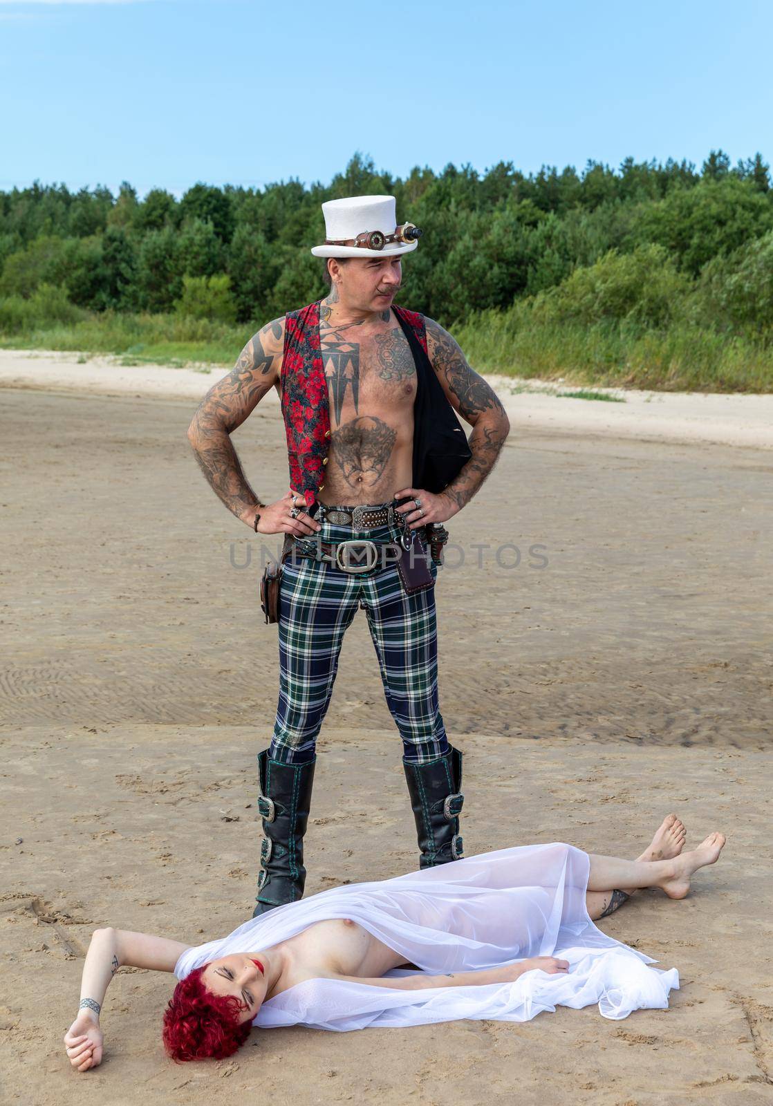 AINAZI, LATVIA – Jul 29, 2019: Love story. Non-traditional wedding photo shoot on the shores of the Baltic Sea. Nude bride in a veil and a spectacular groom