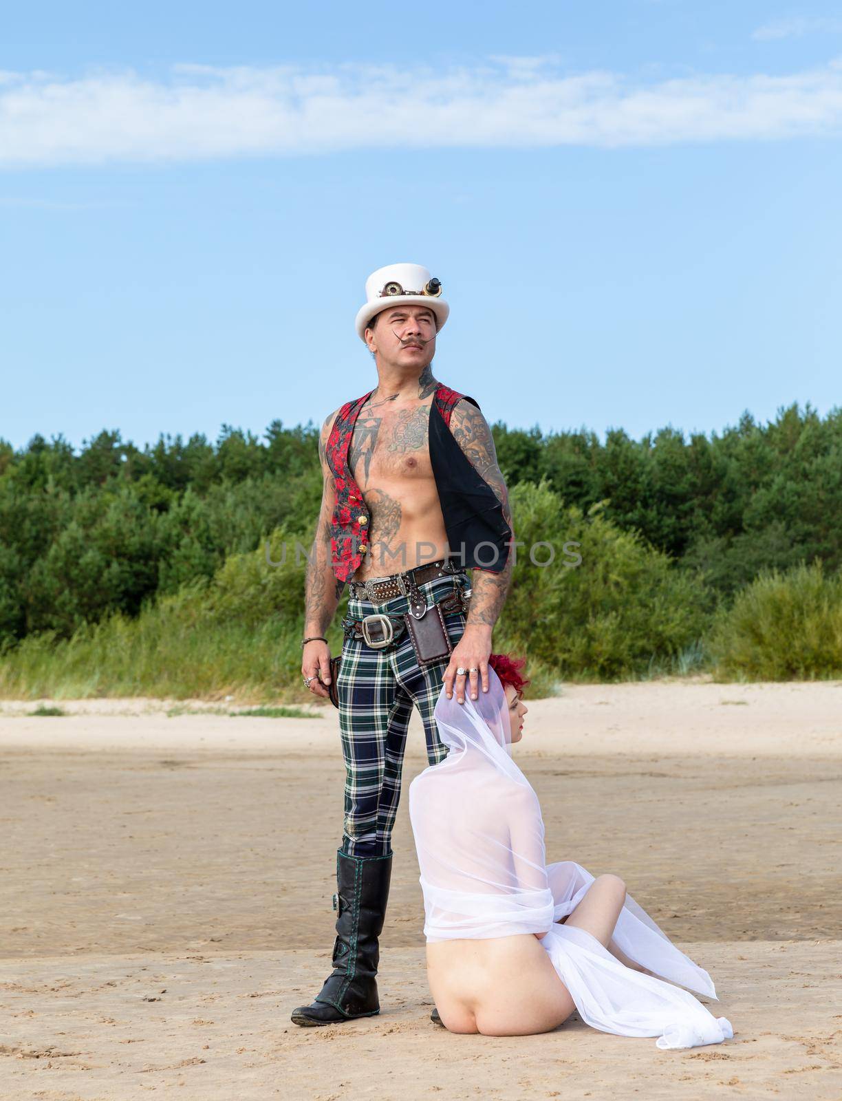 AINAZI, LATVIA – Jul 29, 2019: Love story. Non-traditional wedding photo shoot on the shores of the Baltic Sea. Nude bride in a veil and a spectacular groom