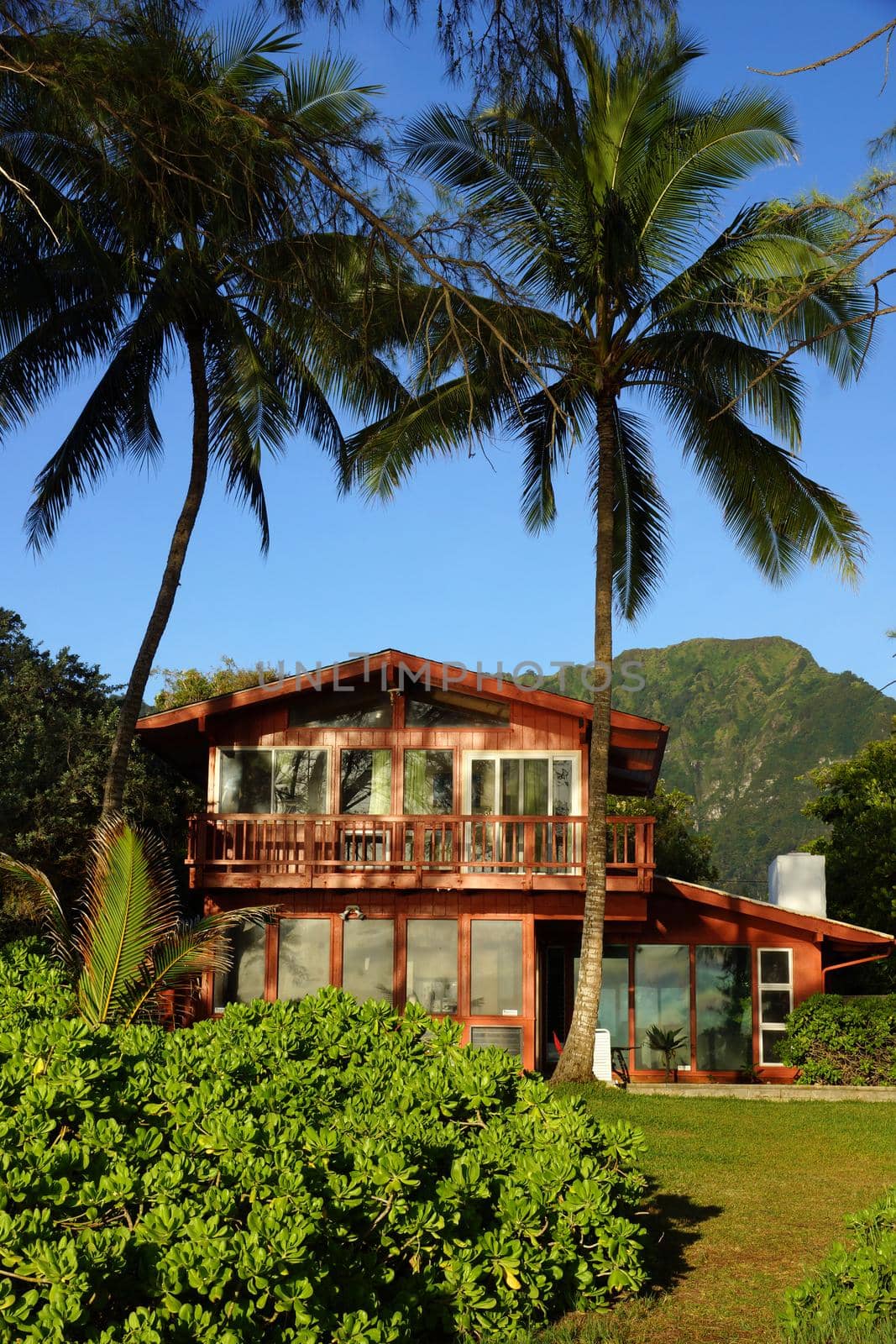 Red Beach House and coconut trees in Waimanalo on a Beautiful Day on Oahu, Hawaii.                               
