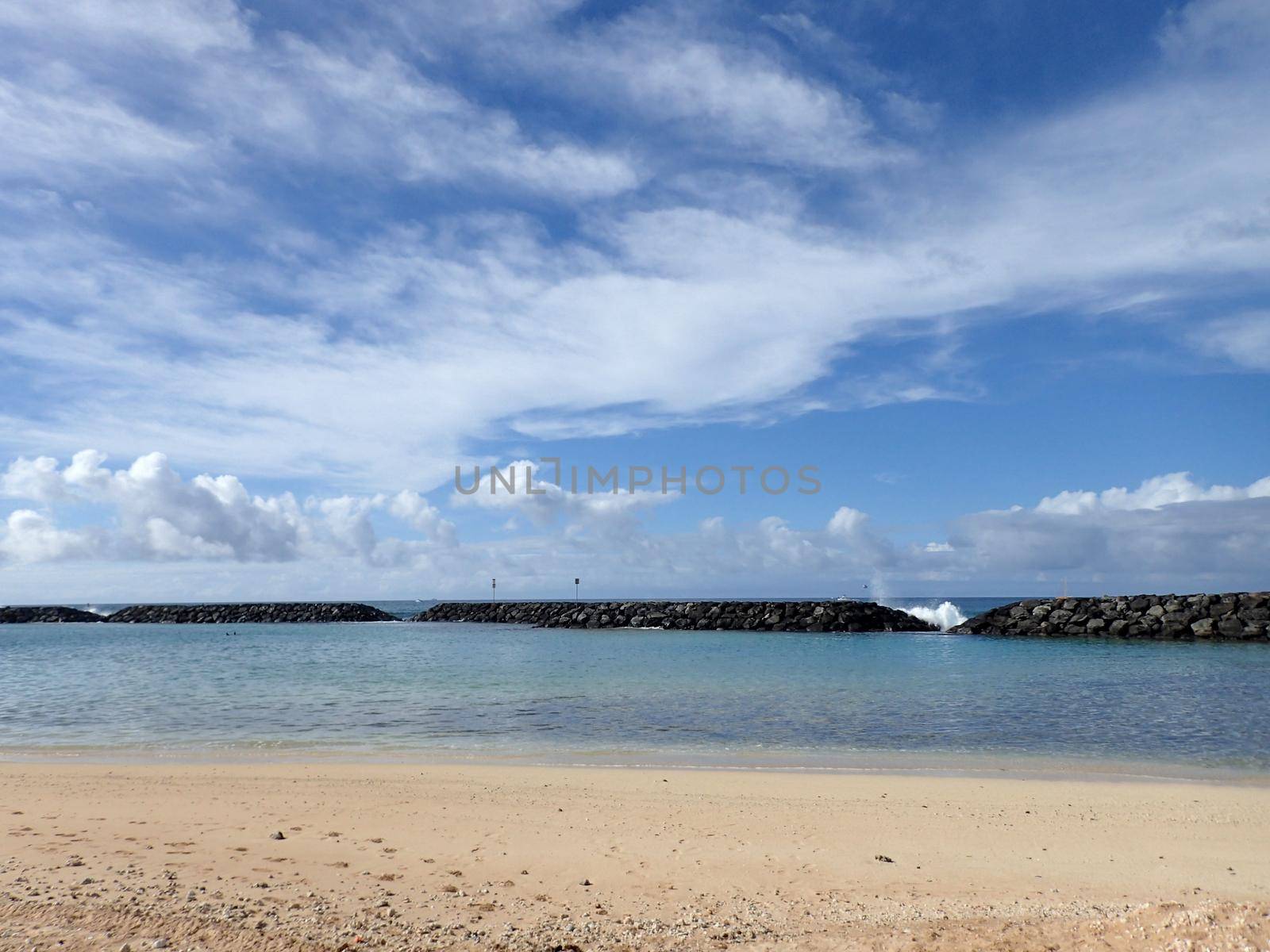 Beach on Magic Island in Ala Moana Beach Park with wave breaking over rocks on the island of Oahu, Hawaii.  On a beautiful day.