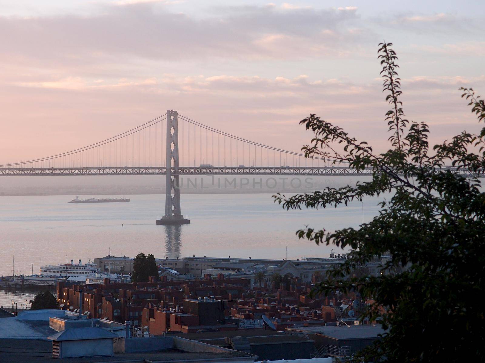 San Francisco Piers and Bay Bridge at Dusk with boat sailing in the bay in California.