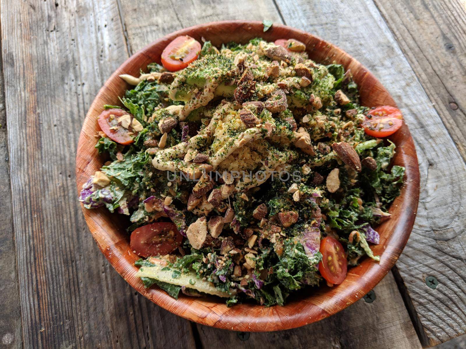 Rainbow Bowl: Kale salad with red cabbage, green onion, carrot, Japanese  cucumbers tossed in ginger tahini dressing.  Served on brown rice.  Topped with avocado, grape tomato, veggie mix, almonds and hummus. 