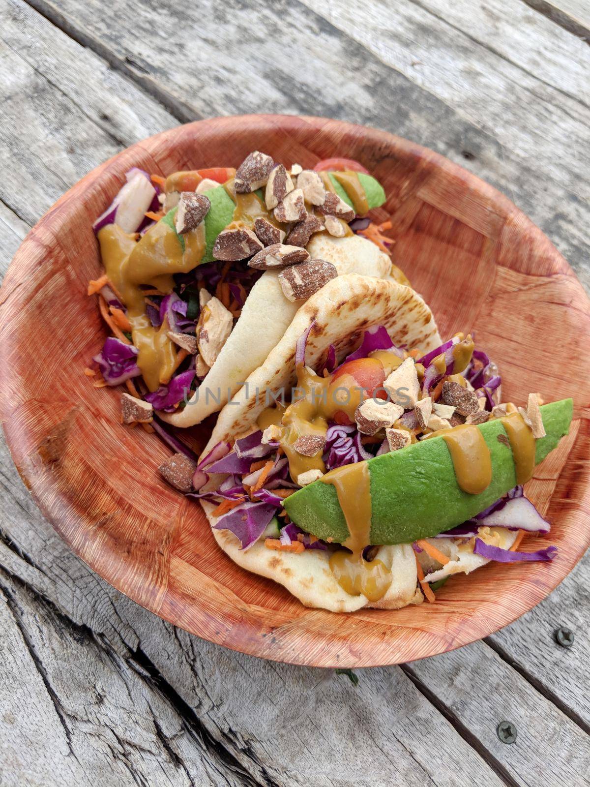 Rainbow Tacos: Veggie mix of red cabbage, green onion, carrot, and Japanese cucumbers.  Served on warm naan with hummus and balsamic drizzle. Topped with avocado, grape tomato, and almonds.