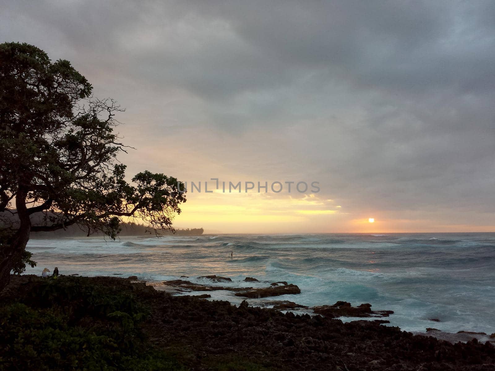 SUP Paddler ride waves as sunsets though the clouds off the coast of Turtle Bay by EricGBVD