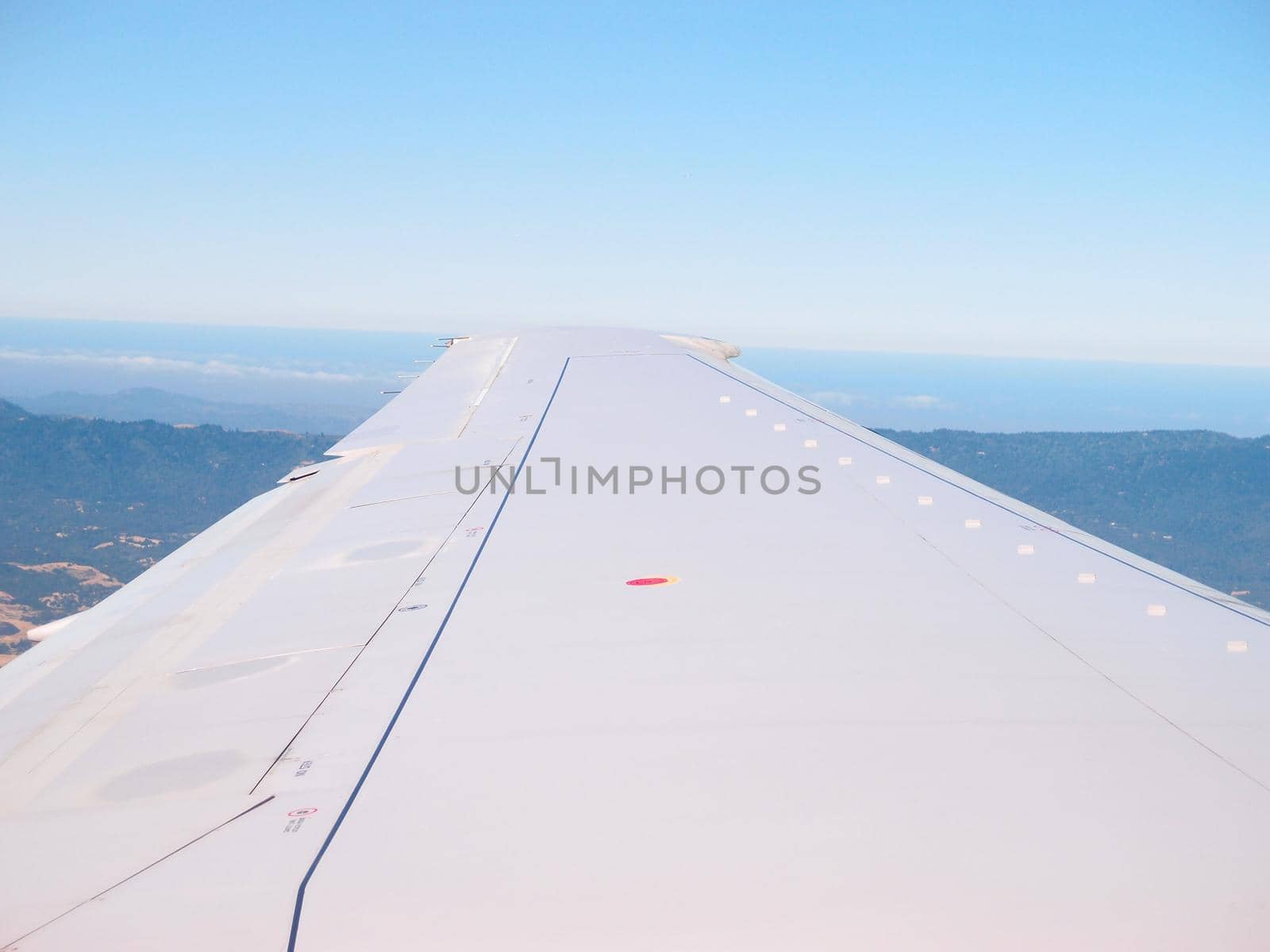 San Francisco - June 13, 2013: Wing of airlines plane flying in the air above city of San Francisco and ocean.