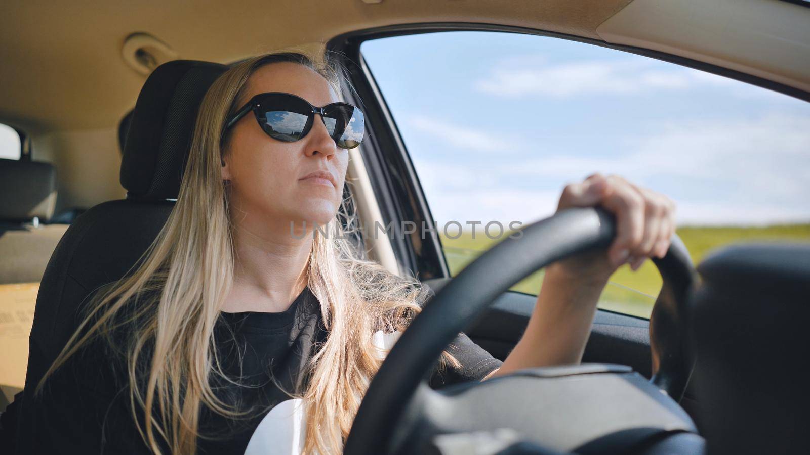 A young woman in a good mood behind the wheel of a car