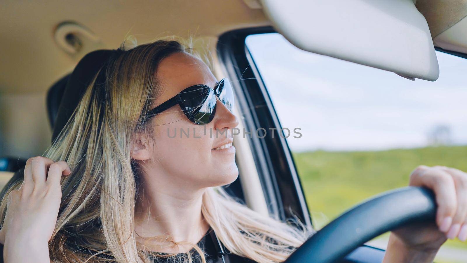 A young woman in a good mood behind the wheel of a car