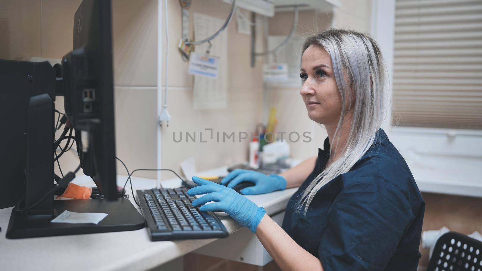 The veterinarian at work is typing on the keyboard at the computer