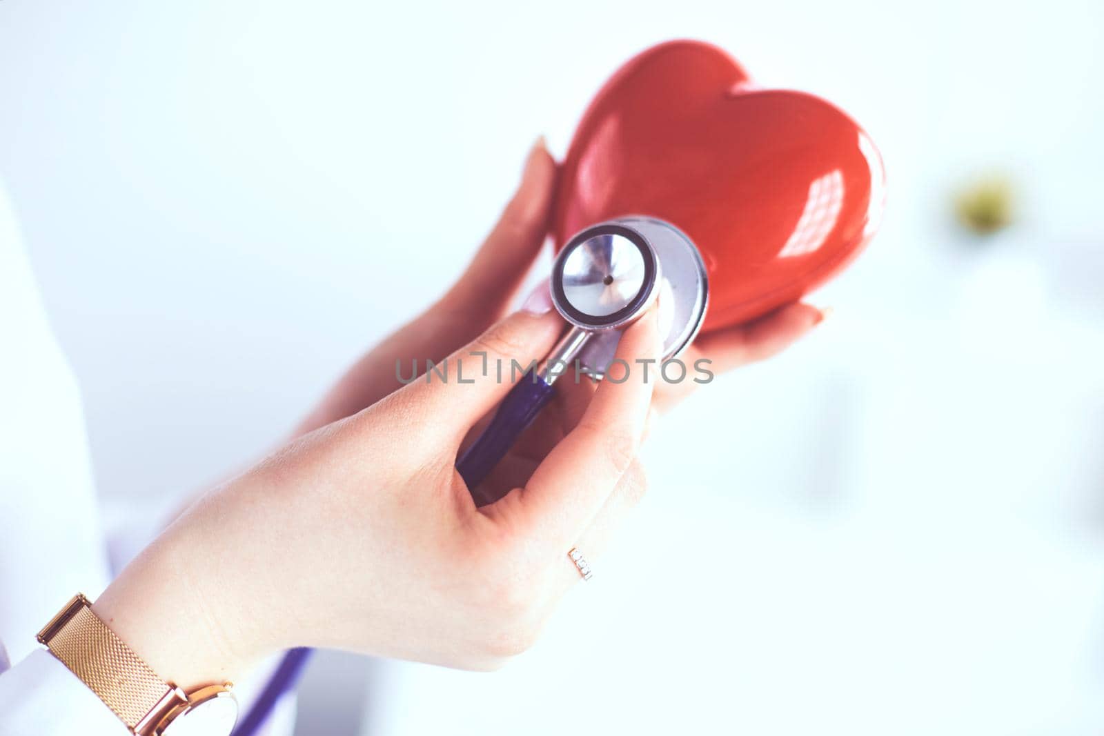A doctor with stethoscope examining red heart, isolated on white background by lenets