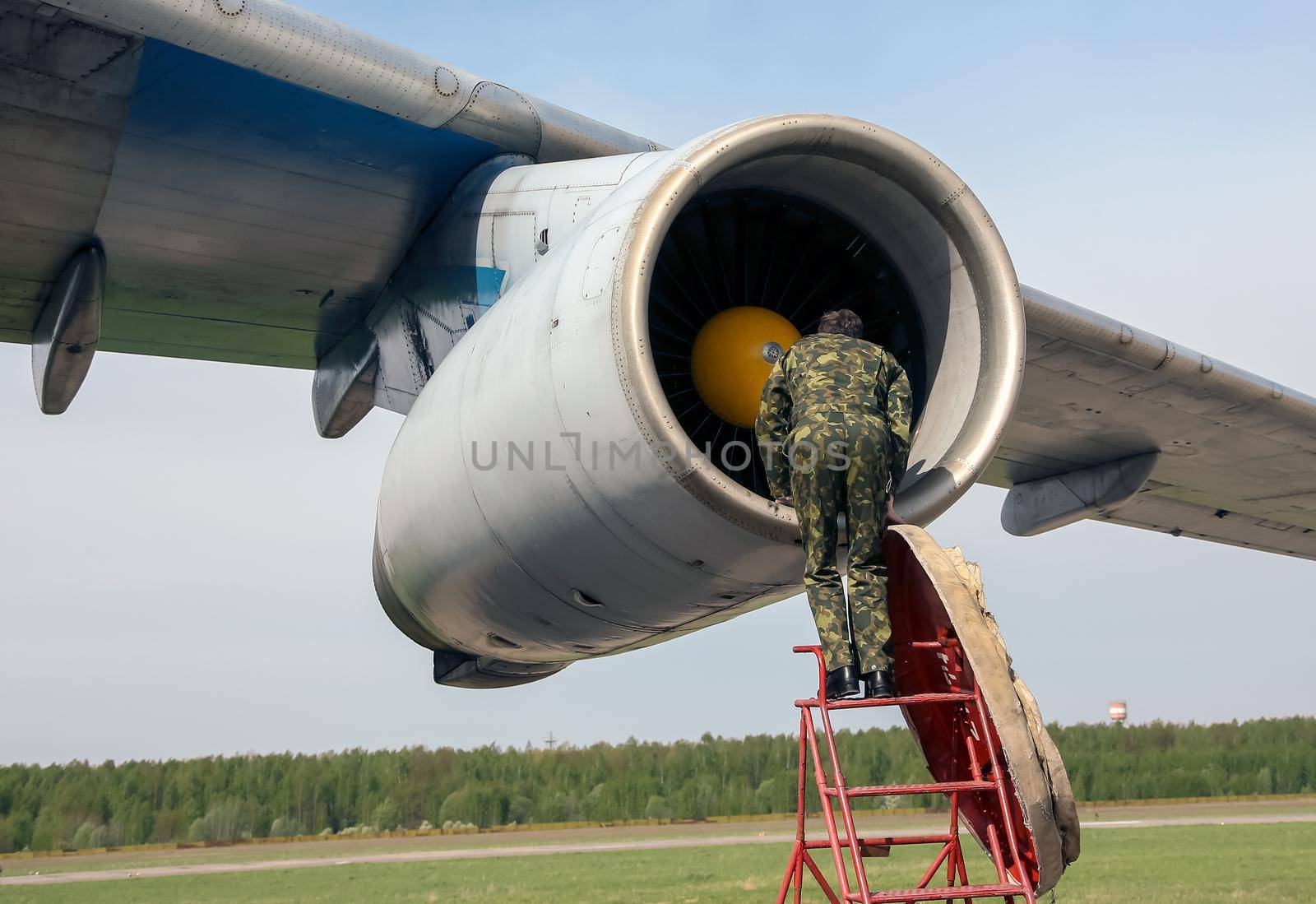 aircraft mechanic checks airplane turbine, engineers, with a large airliner in the background, ground events at the airport