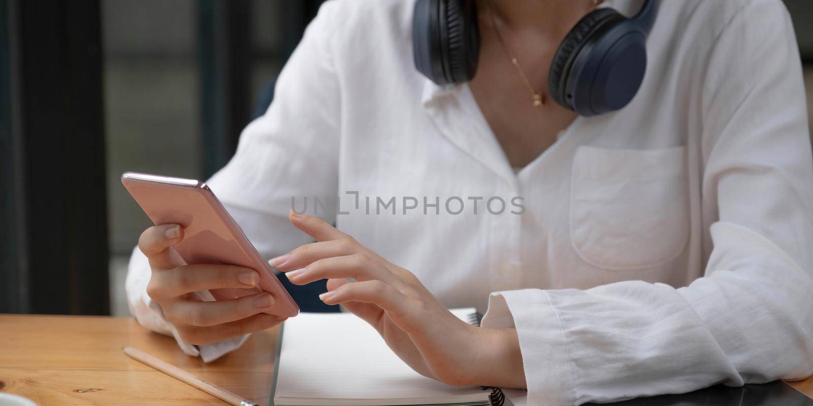 Asian young woman using smart phone at cafe. Smiling woman using smartphone at home, messaging or browsing social networks while relaxing. by wichayada