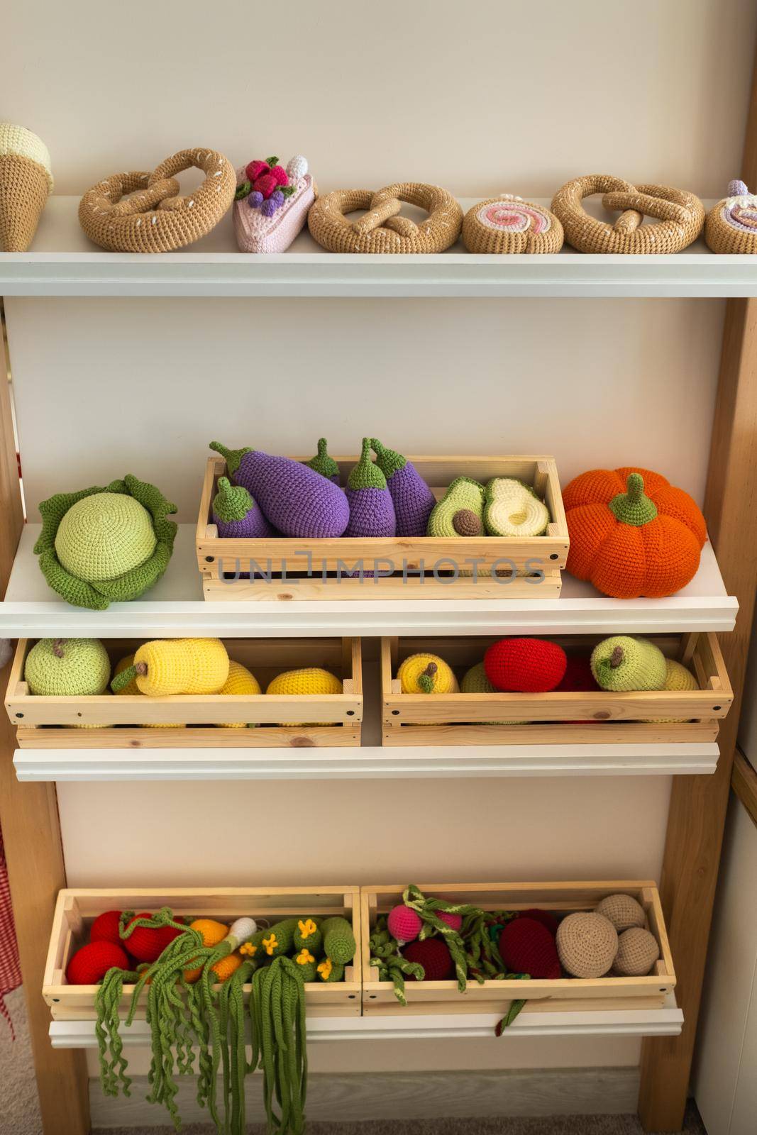 Artificial food in the children's kitchen. On the shelf are vegetables and fruits made of knitted threads.