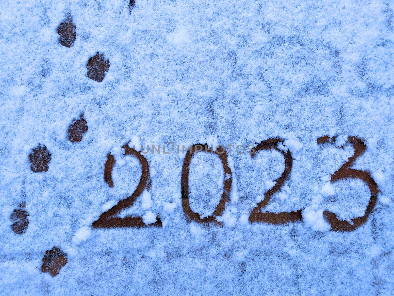 Text Happy New Year 2023 on the snow. Handwritten inscription 2023 and traces of the coming year on white freshly fallen snow. Abstract background photo of upcoming New Year 2023.