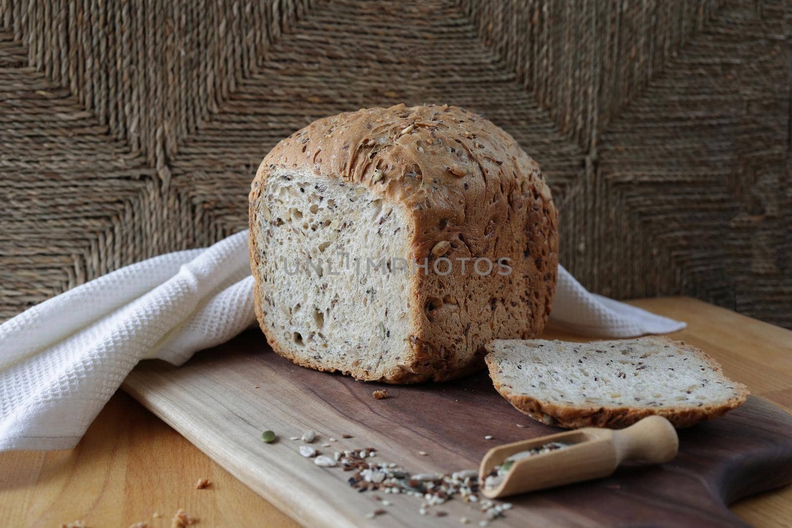 loaf of homemade whole grain bread and a cut slice of bread on a wooden cutting board. Mixture of seeds and whole grains. Healthy eating by Proxima13