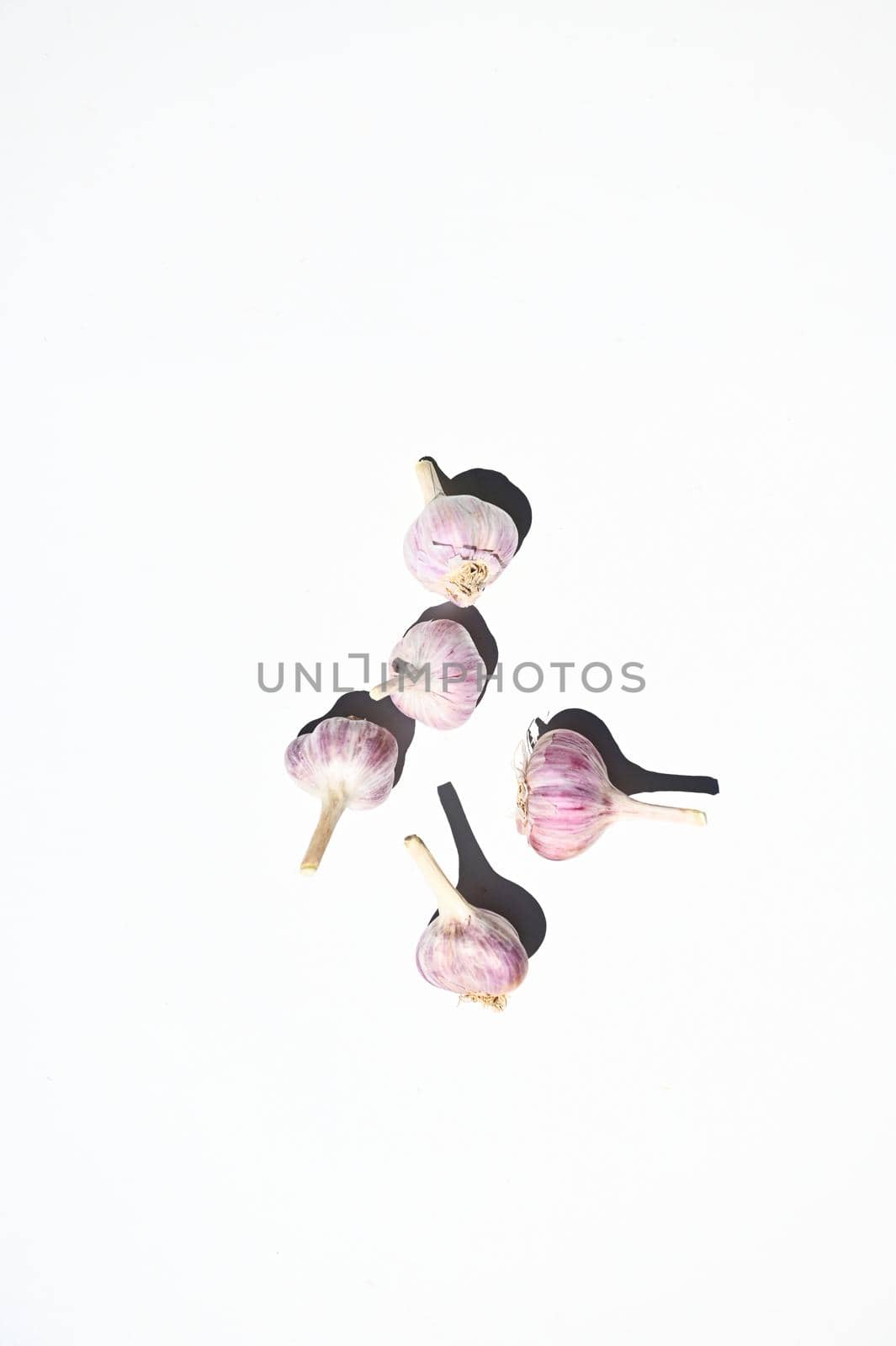 Flay lay of composition of three raw garlic heads, isolated on white background with copy space for advertising text. Web banner. Vertical studio shot