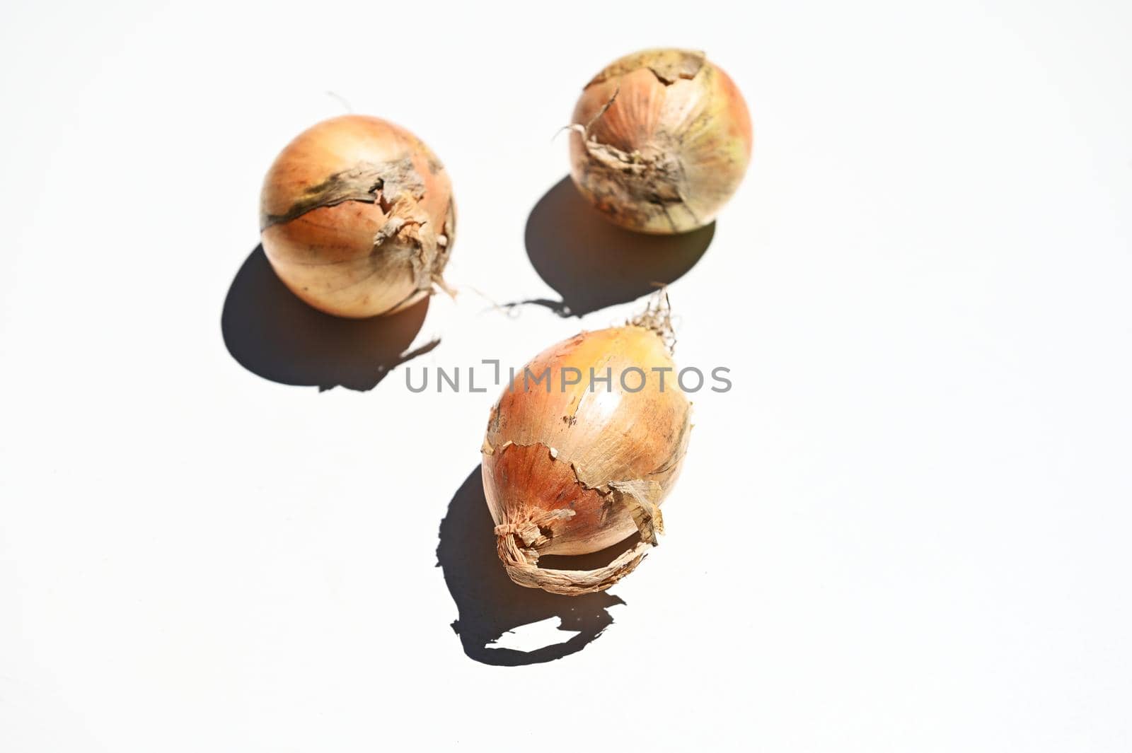 Flay lay of composition of three raw onions, isolated on white background with copy space for advertising text. Web banner. Horizontal studio shot