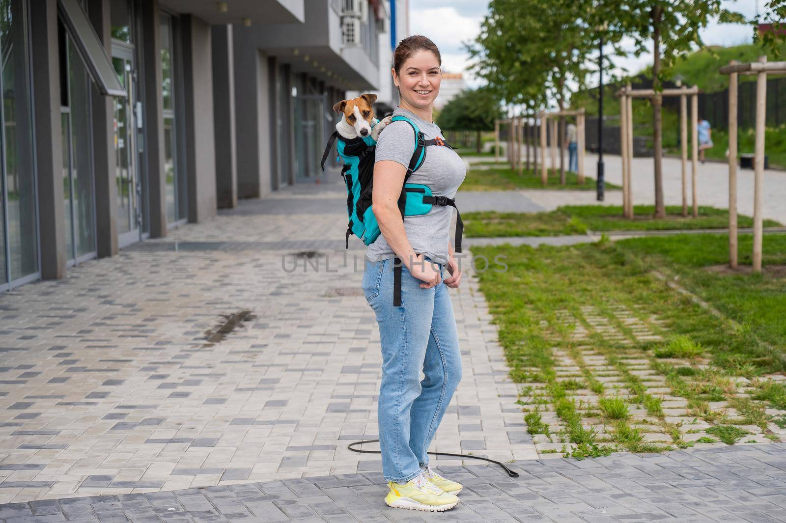 Caucasian woman walking outdoors with dog jack russell terrier in a special backpack