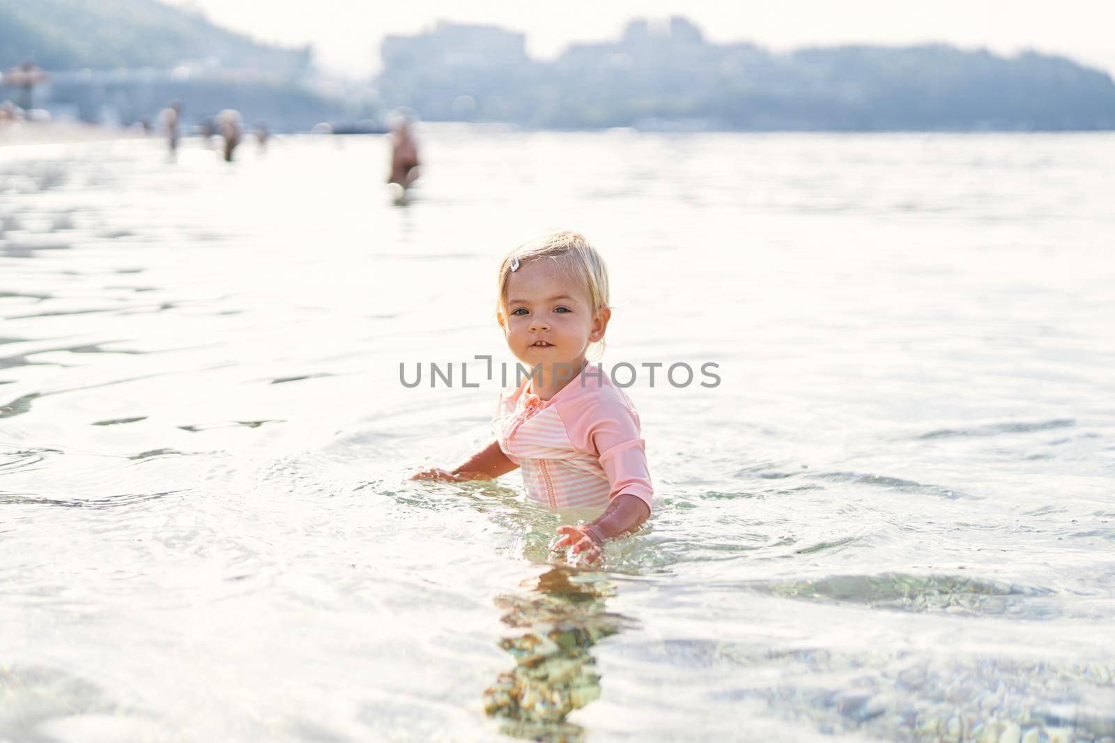 Little girl stands in the sea in shallow. High quality photo