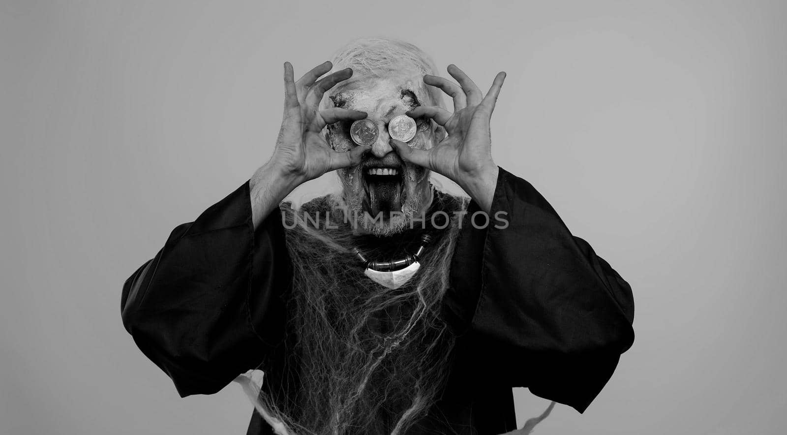 Joyful man with bloody scars face, Halloween zombie showing golden bitcoins. Achievement career wealth, cryptocurrency investment, mining, future technology. Scary wounded undead guy smiles terribly