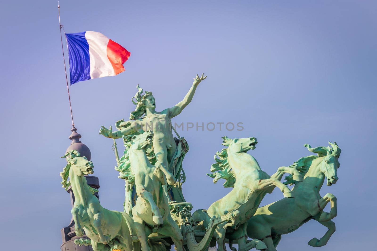 French flag and quadriga chariot of four horses in Paris at clear sky, France
