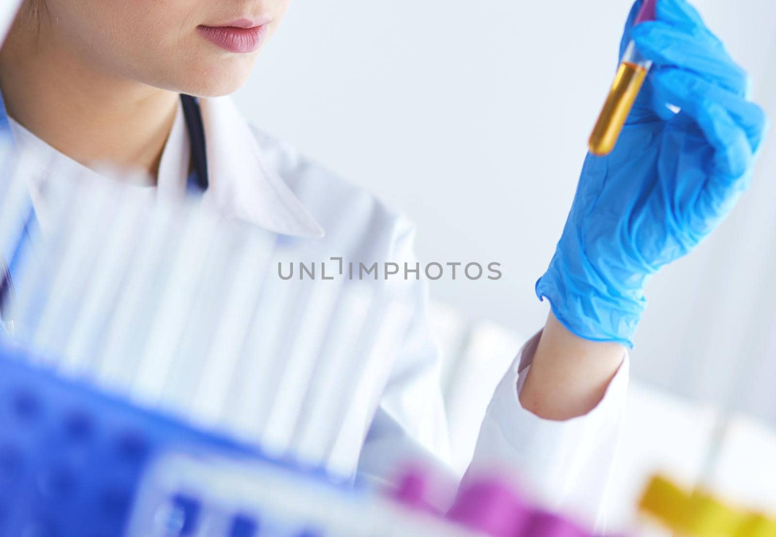 A female medical or scientific researcher or woman doctor looking at a test tube of clear solution in a laboratory .