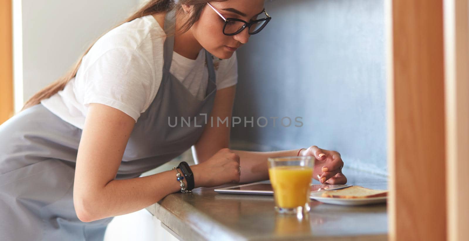 Portrait of young attractive caucasian brunette housewife at kitchen. Morning with cup of coffee and tablet pc.