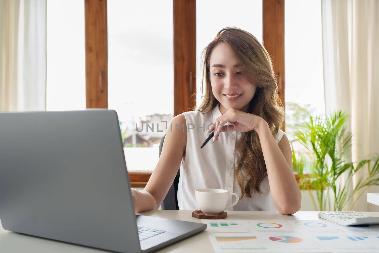 Attractive smiling young asian woman on a video call by laptop computer.