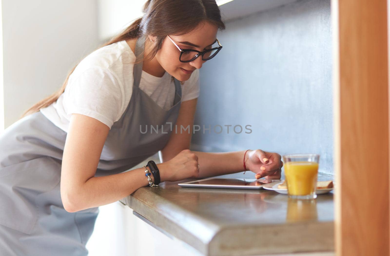 Young woman with orange juice and tablet in kitchen. by lenets