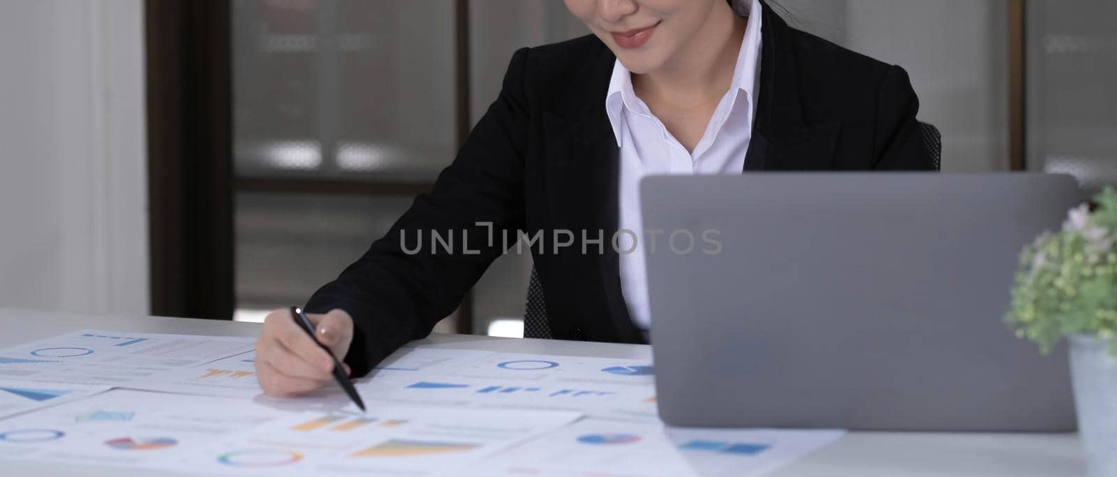 Beautiful smiling Asian businesswoman working pointing on a graph at the office.