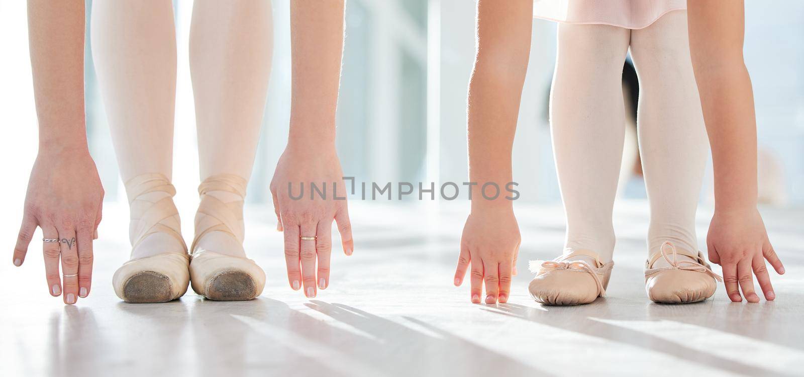 Ballet is like a rose. It is beautiful. two unrecognizable ballerinas stretching in a dance studio. by YuriArcurs