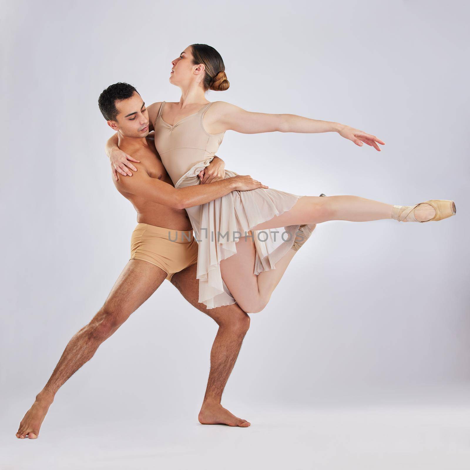 If you do nothing else today, just dance. Studio shot of a young man and woman performing a ballet recital against a grey background. by YuriArcurs