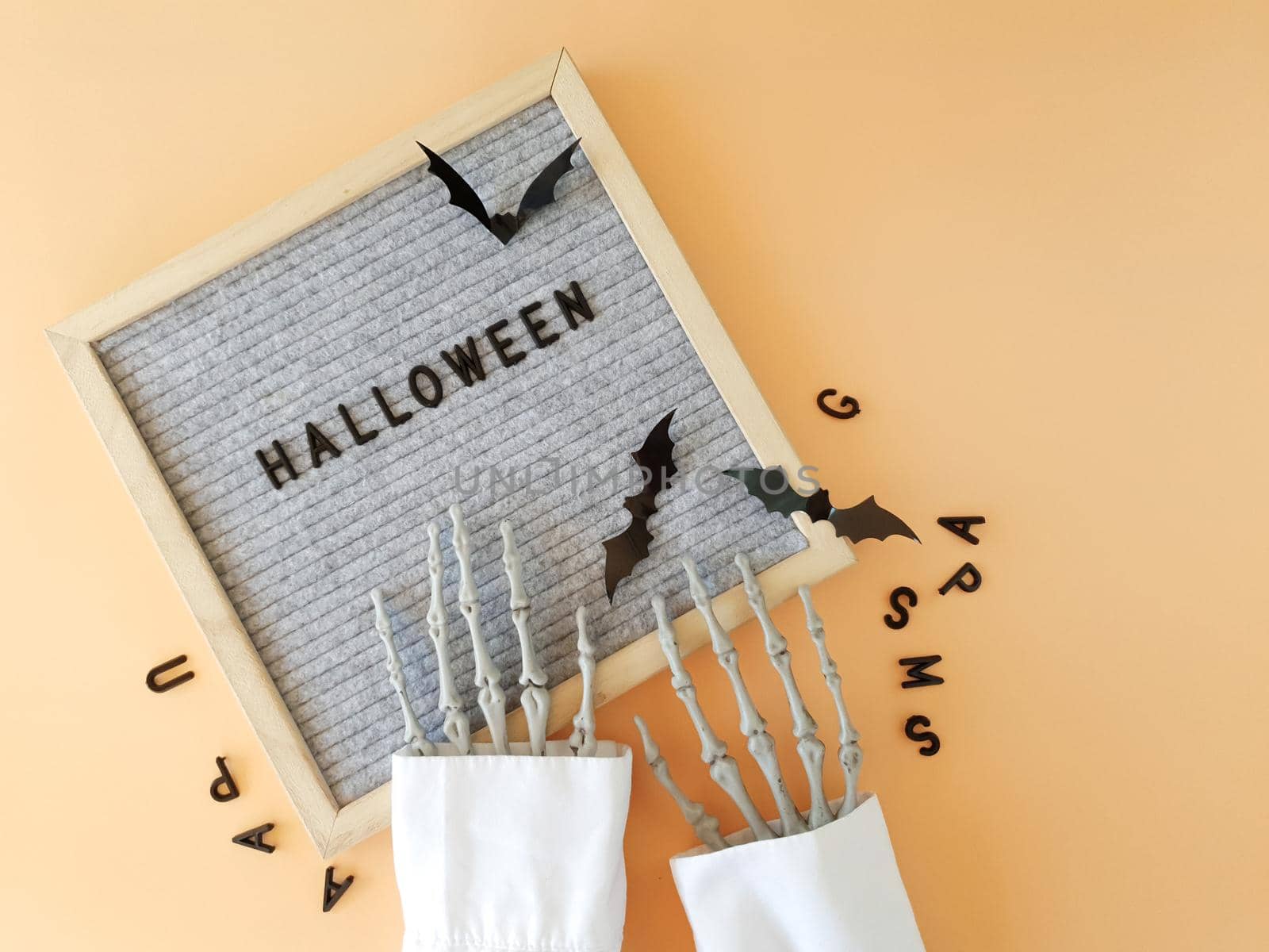 The skeleton's hand collects the word Halloween in a frame by Spirina