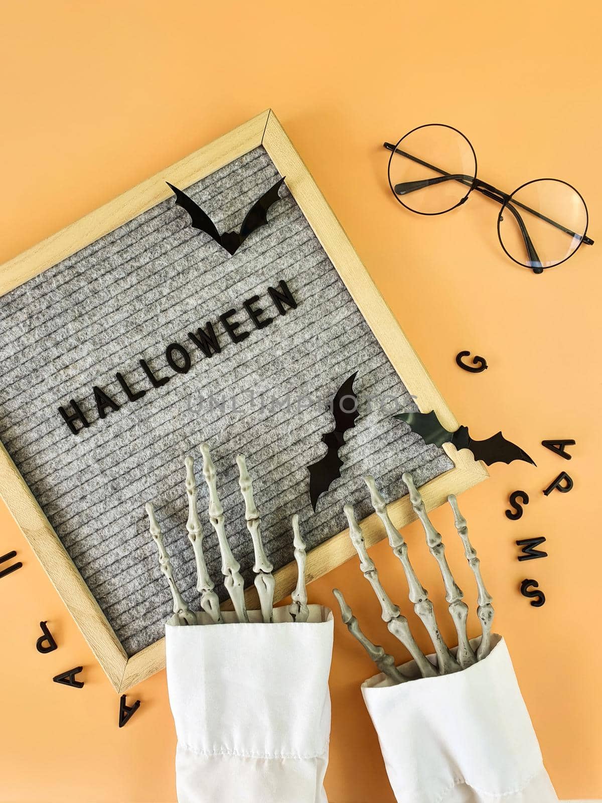 The skeleton's hand collects the word Halloween in a frame . High quality photo