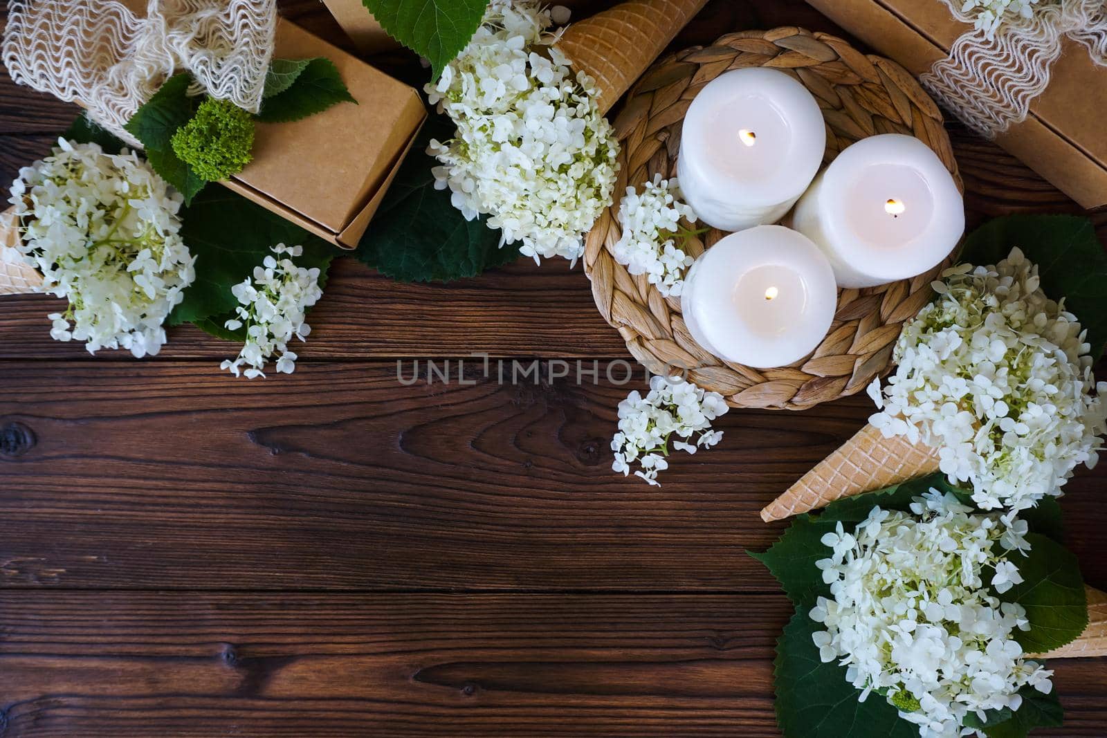 There are lighted candles, gifts and flowers on a dark wooden table. High quality photo