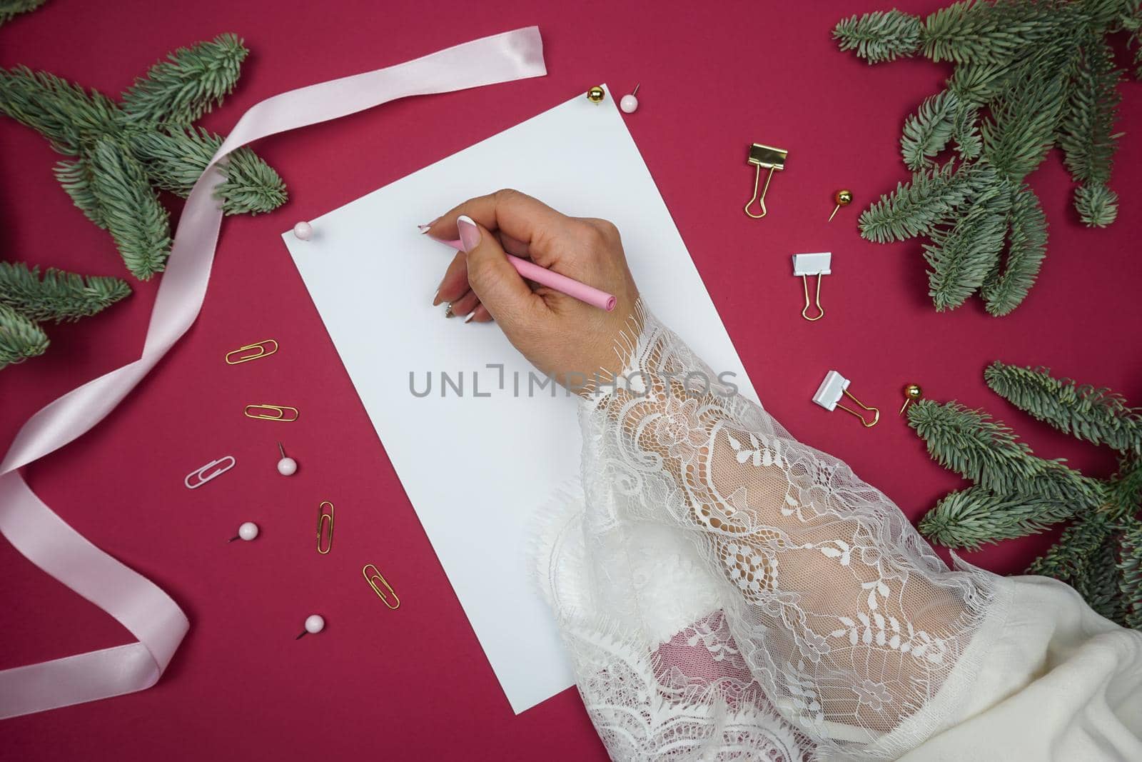 A woman's hand writes plans, fir branches lie nearby. High quality photo