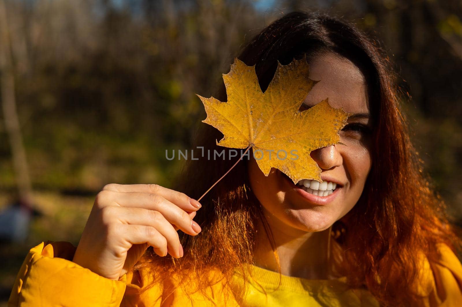 Red-haired Caucasian woman holding a fallen maple leaf. Autumn Walk