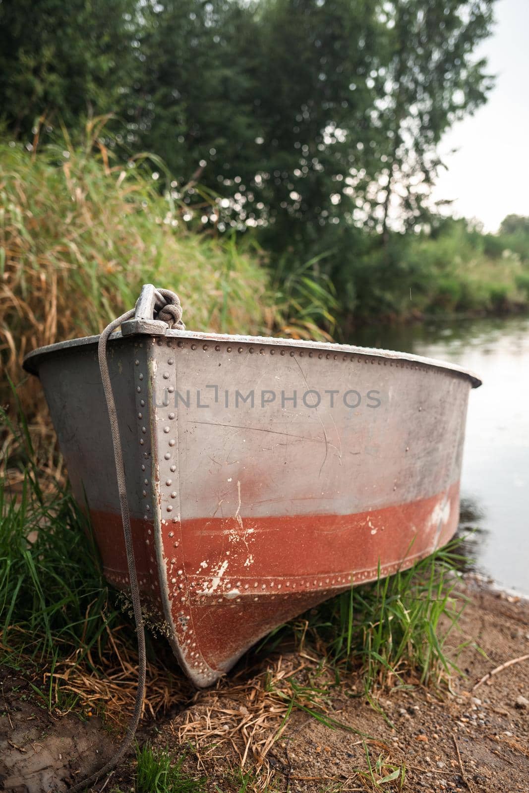 A motor boat is parked at the shore of a lake or river in the evening at sunset or early in the morning. The boat is in a quiet place next to the reeds and is ready for fishing.