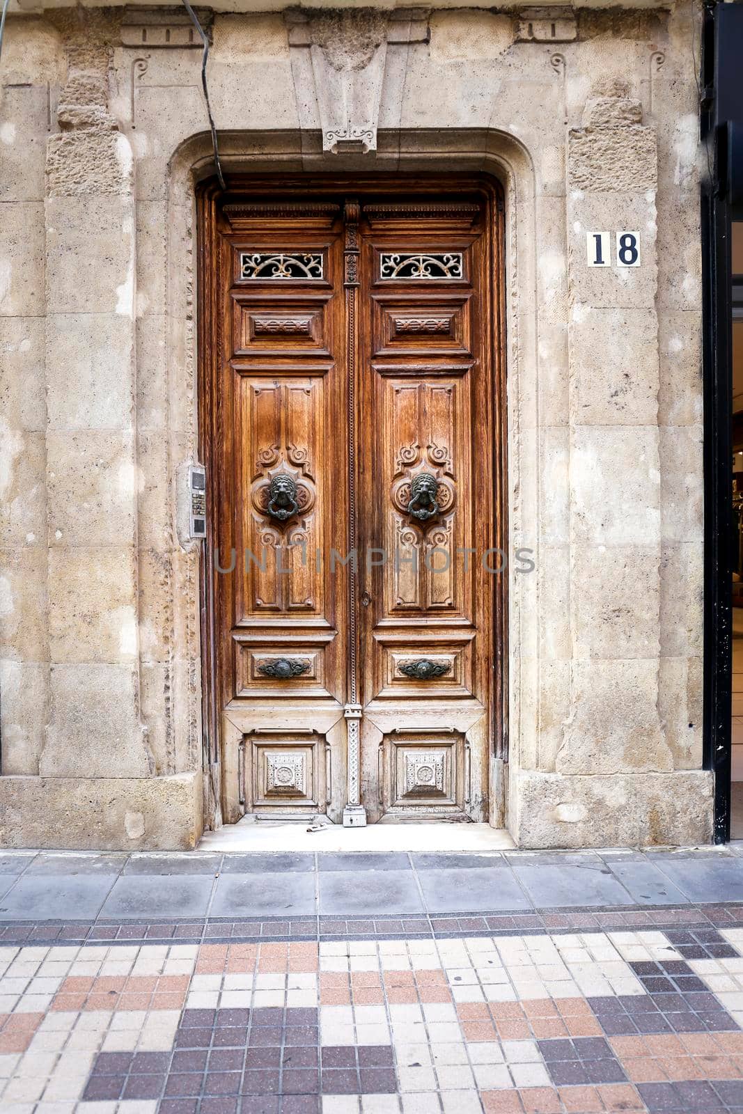 Cartagena, Murcia, Spain- July 18, 2022: Beautiful carved wooden door and vintage lion face shaped knocker in Spain