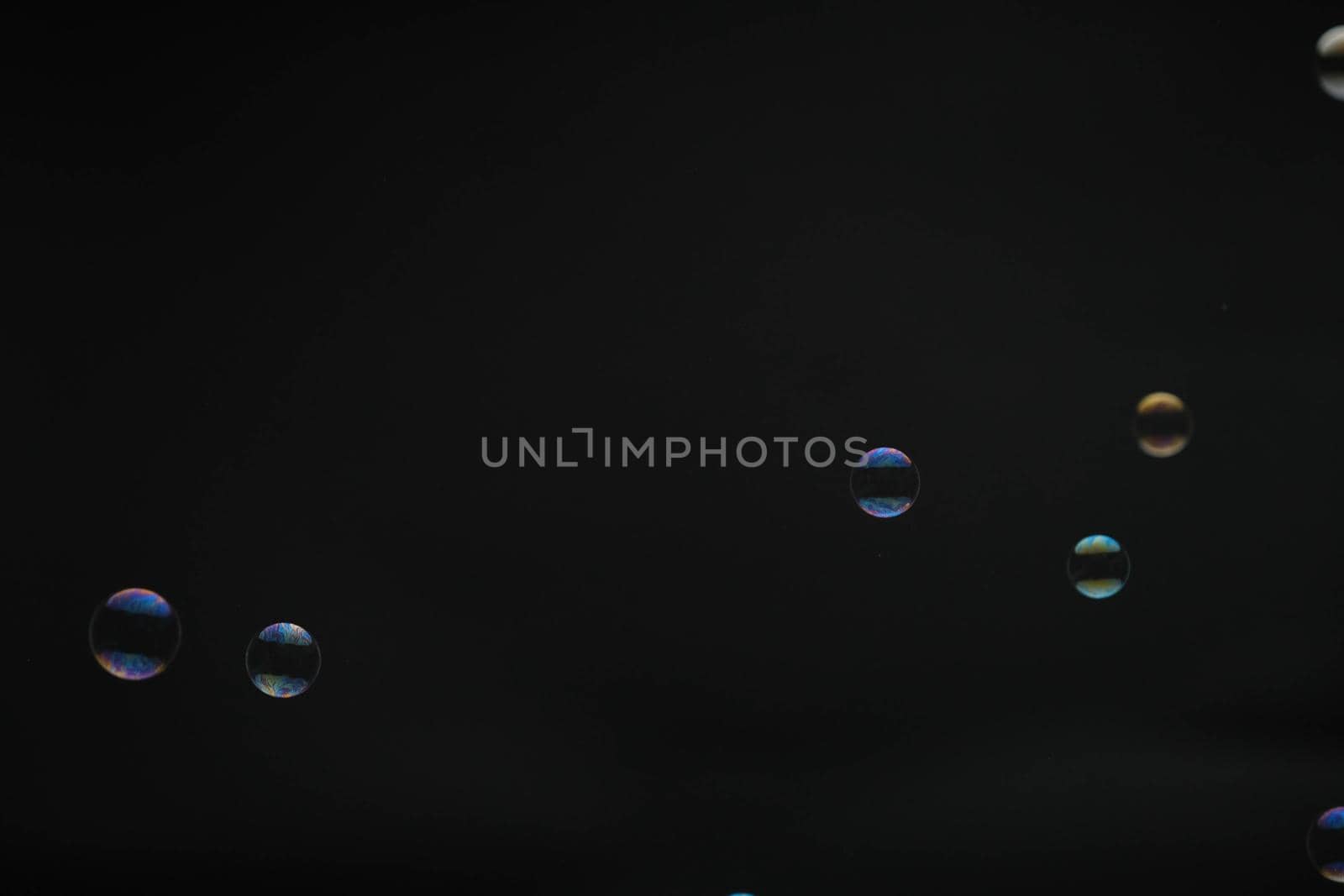 Flying soap bubbles on black background. Abstract soap bubbles with colorful reflections. Soap bubbles in motion background.